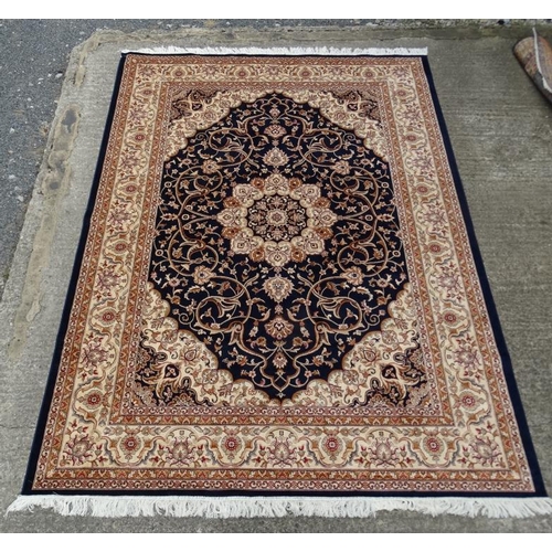 60 - Carpet / Rug:    A machine made Persian Keshan style carpet with midnight blue / black central groun... 