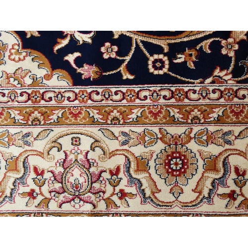 60 - Carpet / Rug:    A machine made Persian Keshan style carpet with midnight blue / black central groun... 