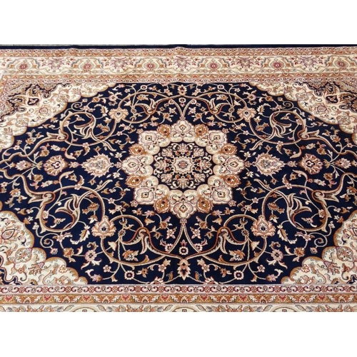 60 - Carpet / Rug:    A machine made Persian Keshan style carpet with midnight blue / black central groun... 