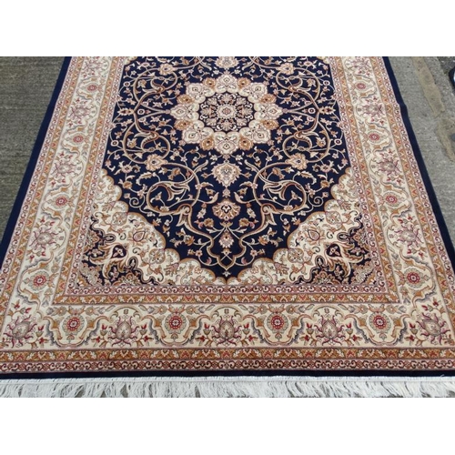 60 - Carpet / Rug:    A machine made Persian Keshan style carpet with midnight blue / black central groun... 