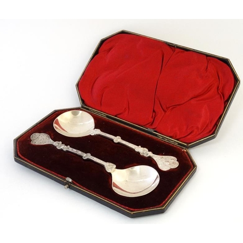 623 - A cased pair of white metal spoons with cast figural decoration to handles. Marked RFM  7'' long . T... 