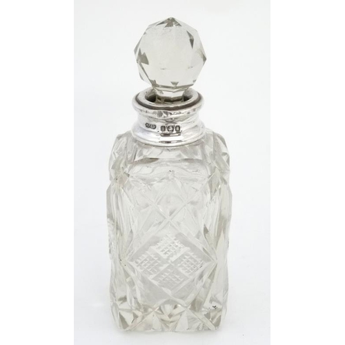 633 - A cut glass perfume bottle of square form with silver collar and faceted ball stopper. The collar ha... 