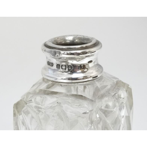 633 - A cut glass perfume bottle of square form with silver collar and faceted ball stopper. The collar ha... 