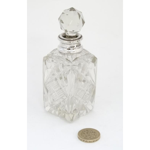 633 - A cut glass perfume bottle of square form with silver collar and faceted ball stopper. The collar ha... 