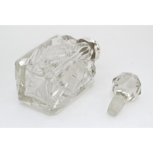 633 - A cut glass perfume bottle of square form with silver collar and faceted ball stopper. The collar ha... 