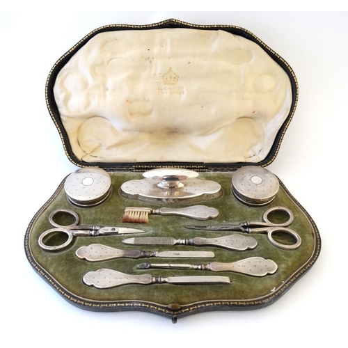 643 - A cased manicure set with silver topped glass pots, silver handled nail buffer, brush, scissors, fil... 