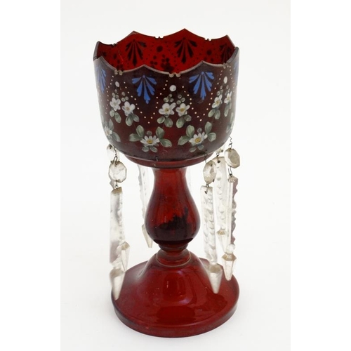 683 - A ruby glass pedestal table lustre with enamelled floral decoration and lustre drops. 12'' high