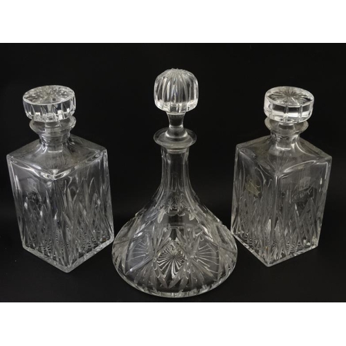 689 - A pair of cut glass/ crystal decanters of squared form together with a ships decanter. The tallest 1... 