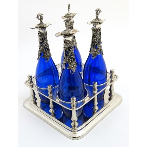 730 - A 21stC silver plate stand containing four blue glass bottles with silver plated mounts having fruit... 