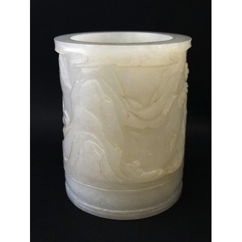 818 - A Chinese white jade cylindrical brush pot with relief decoration of figures playing board games in ... 