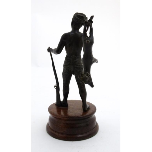 820 - A c.1900 cast bronze figure of a hunter holding a rifle and carrying a small antelope across his sho... 