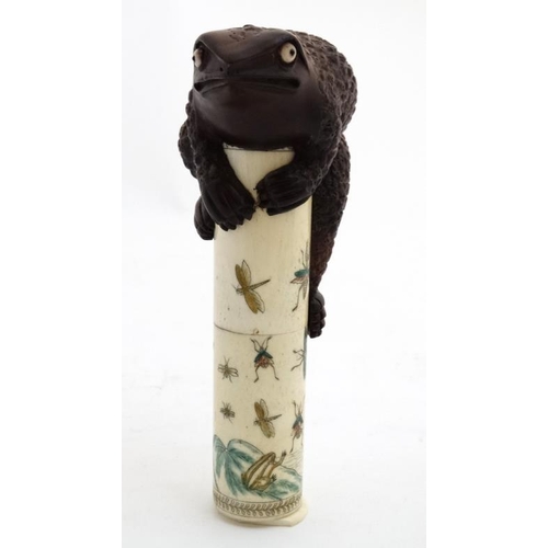 821 - An Oriental bone scroll holder of cylindrical form with shibyama decoration and surmounted by a toad... 