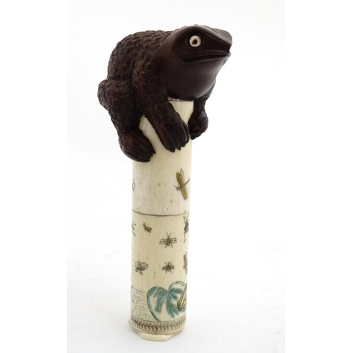 821 - An Oriental bone scroll holder of cylindrical form with shibyama decoration and surmounted by a toad... 