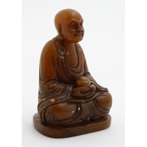 822 - An oriental carved hardstone buddha holding a cylindrical utensil set with many semi precious stone ... 