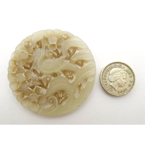 832 - An oriental white jade pierced disc with image of bird amongst prunus 2 1/2'' diameter