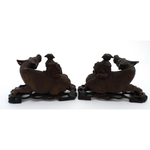 840 - A pair of Chinese carvings formed as children on the backs of water buffaloes on stands , representi... 