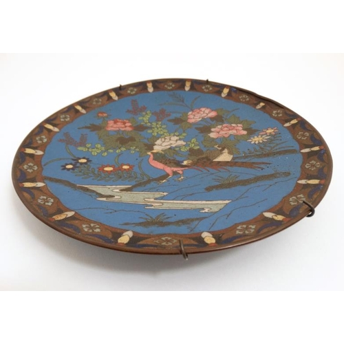 850 - An Oriental Cloisonne charger depicting a pheasant amongst flowering foliage 9 1/2'' diameter