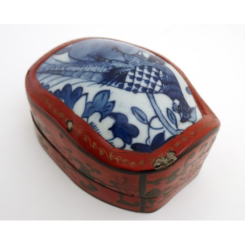 866 - A Chinese shaped red lacquered box and cover with gilt decoration and blue and white ceramic panel w... 