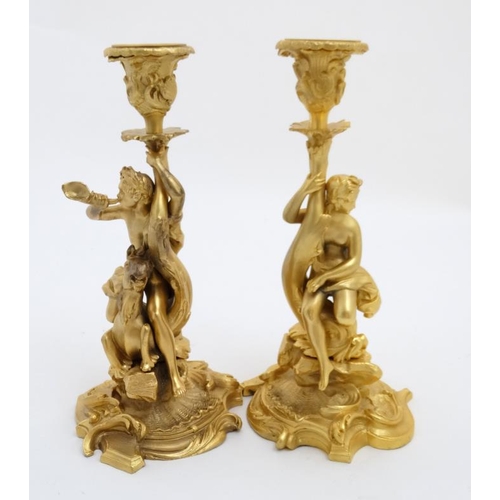 892 - A pair of gilded bronze candlesticks depicting a figure on seahorse and another of a dolphin 1 1/2''... 