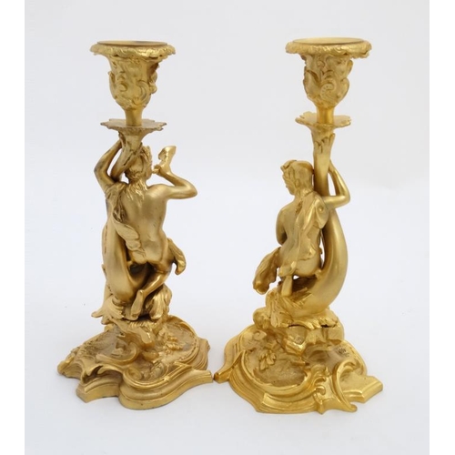 892 - A pair of gilded bronze candlesticks depicting a figure on seahorse and another of a dolphin 1 1/2''... 