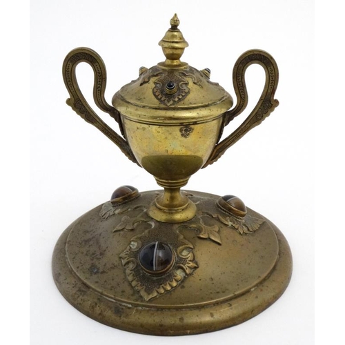 904 - A 19thC brass inkstand with trophy cup style inkwell on circular base and set with 6 banded agate ca... 