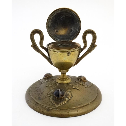 904 - A 19thC brass inkstand with trophy cup style inkwell on circular base and set with 6 banded agate ca... 