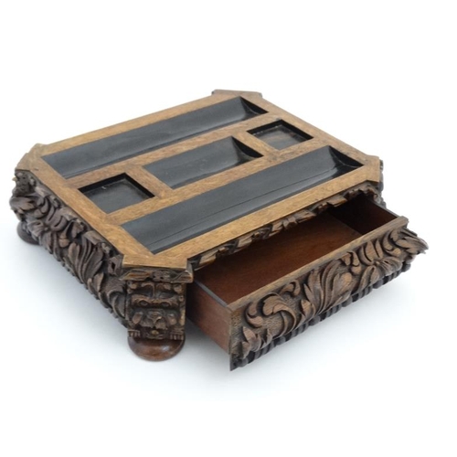 938 - A Victorian inkstand / Standish of carved oak with pen rest sections, squared inkwell section and ni... 