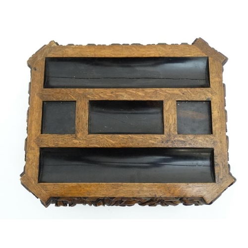 938 - A Victorian inkstand / Standish of carved oak with pen rest sections, squared inkwell section and ni... 