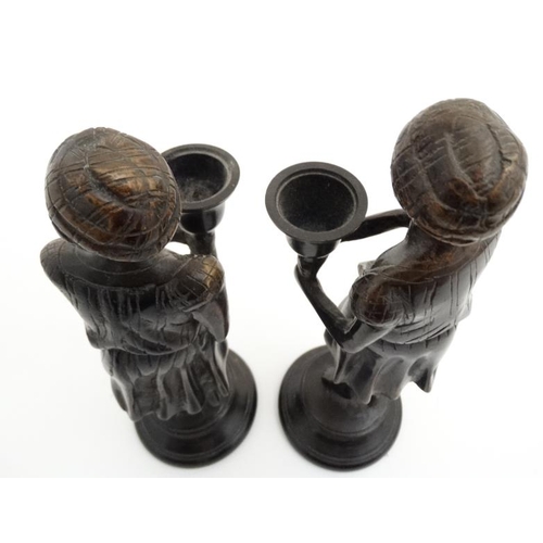 952 - A pair of cast bronze candlesticks in the form of eastern figures wearing a turban on a circular soc... 