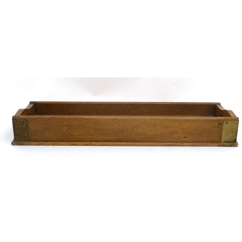 961 - An early 20thC blonde oak desk top book trough / tray with two pierced carry handles and brass corne... 