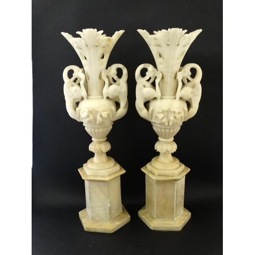 986 - A pair of 19thC alabaster vases having pairs of wyvern handles, the urns mounted upon hexagonal socl... 