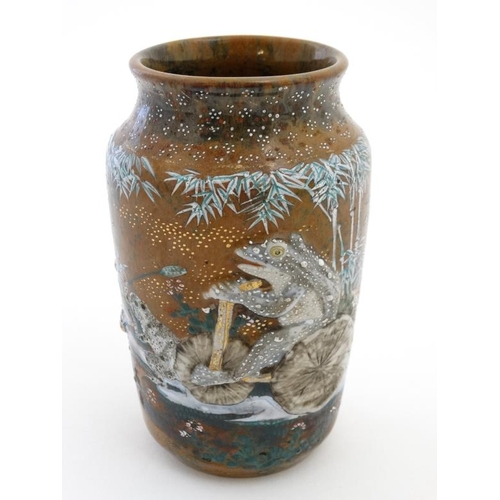 410 - A Japanese Meiji style vase decorated in relief with frogs including one riding a bicycle on a brown... 