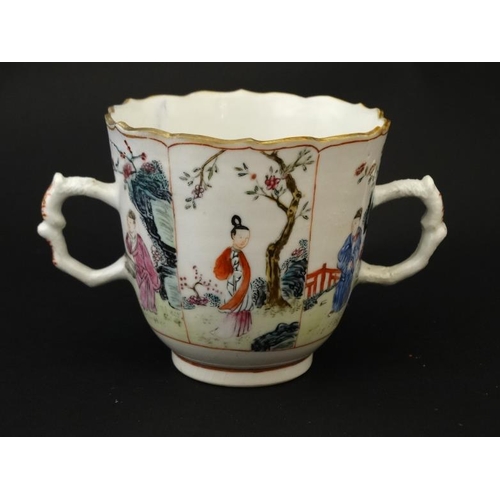 413 - An Oriental famille rose two handled mug and saucer , decorated with panels depicting figures in gar... 