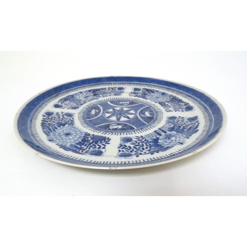 428 - An Chinese blue and white plate decorated with panels of Chrysanthemums and other stylised flowers a... 