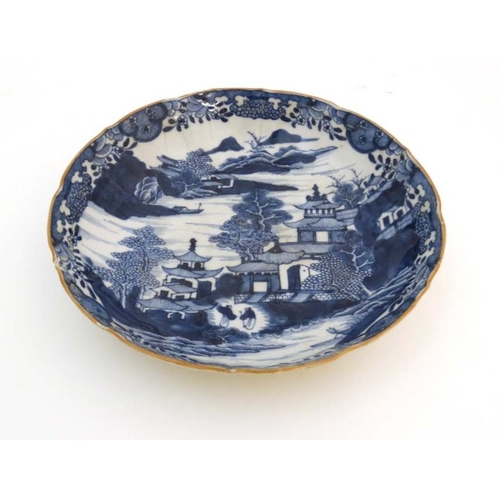 439 - An oriental style blue and white dish. Depicting figures in an oriental landscape with pagodas and m... 