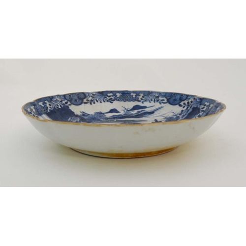 439 - An oriental style blue and white dish. Depicting figures in an oriental landscape with pagodas and m... 