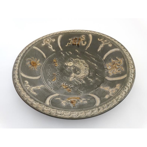 455 - A large Chinese charger in celadon style green and decorated in white with image of Koi carp to cent... 