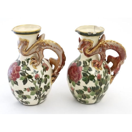 459 - A pair of Continental jugs decorated in an Oriental style with 3 clawed dragon handles and flowering... 