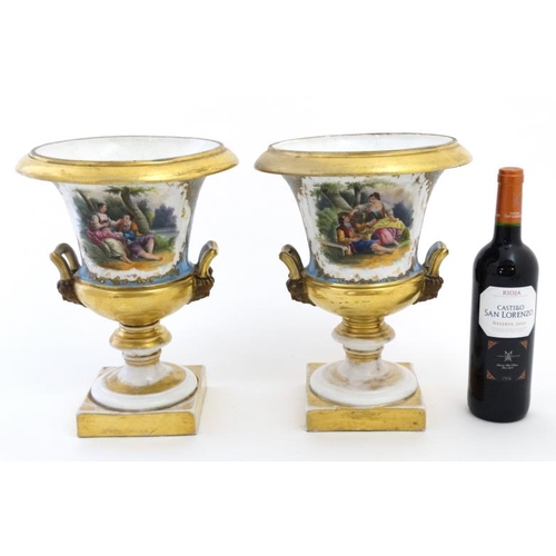 476 - A pair of hand painted Sevres ? twin handled campagna urns, each decorated with a young seated coupl... 