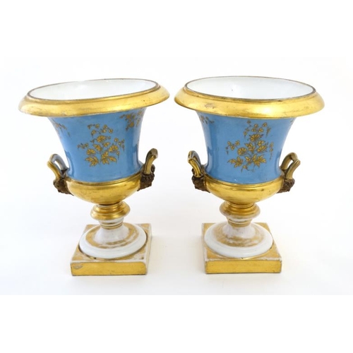 476 - A pair of hand painted Sevres ? twin handled campagna urns, each decorated with a young seated coupl... 