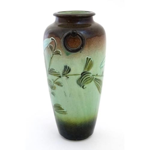 479 - A Moorcroft style twin handled vase decorated with tube lined trumpet flowers in shades of green on ... 