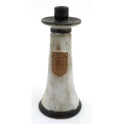 503 - A Continental studio pottery Tavern tall handled candle stick, having brown shield to front depictin... 