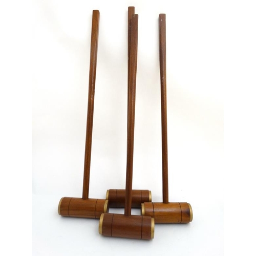 118 - A set of 4 20thC wooden croquet mallets, having gilt painted bands to edges. 40'' high. (4)