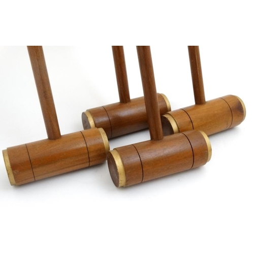 118 - A set of 4 20thC wooden croquet mallets, having gilt painted bands to edges. 40'' high. (4)