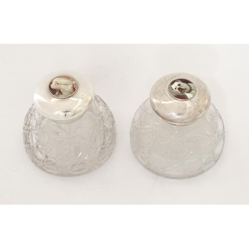 284 - Two cut glass inkwells having silver plated hinged tops with later applied cabochons depicting dogs ... 