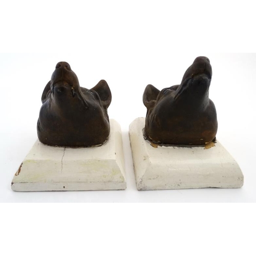 69 - A pair of 19thC cast iron stylised fox masks on squared plinths. For external use 8'' deep x 6 3/4''... 