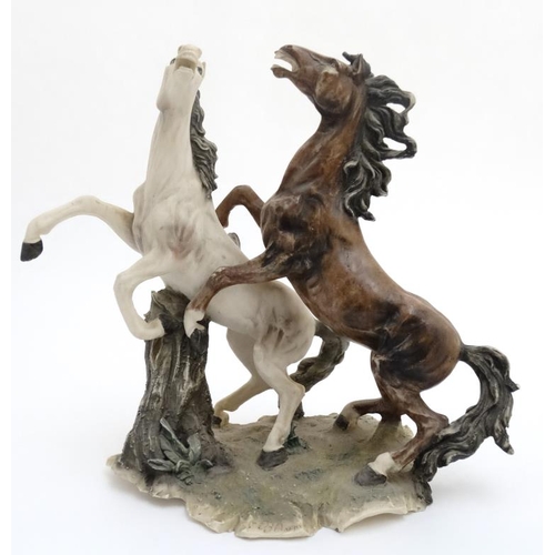 76 - A modern resin polychrome sculpture of two rearing horses , signed B Auzot. 15'' high.