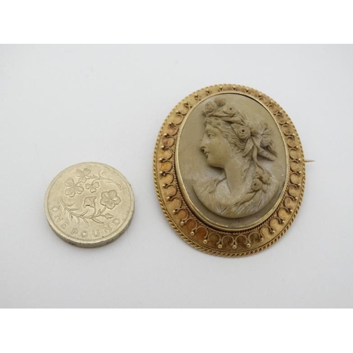 1003 - Grand Tour Jewellery : A 19thC lava cameo brooch depicting the head of a classical woman within a gi... 