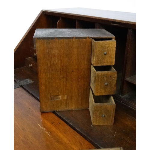 176 - A Georgian oak bureau opening to reveal a fitted interior over two short over three graduated long d... 