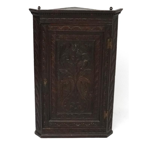 177 - A Georgian carved oak corner cupboard opening to reveal 3  green shaped shelves within. 38 3/4'' hig... 